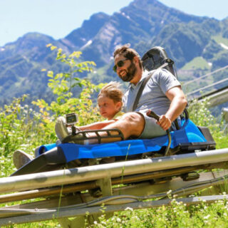 Ein Vater mit seinem Sohn auf einer Sommerrodelbahn.