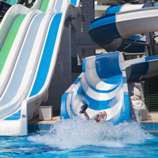 Ein Kind fliegt ins Wasser am Ende einer Wasserrutsche.